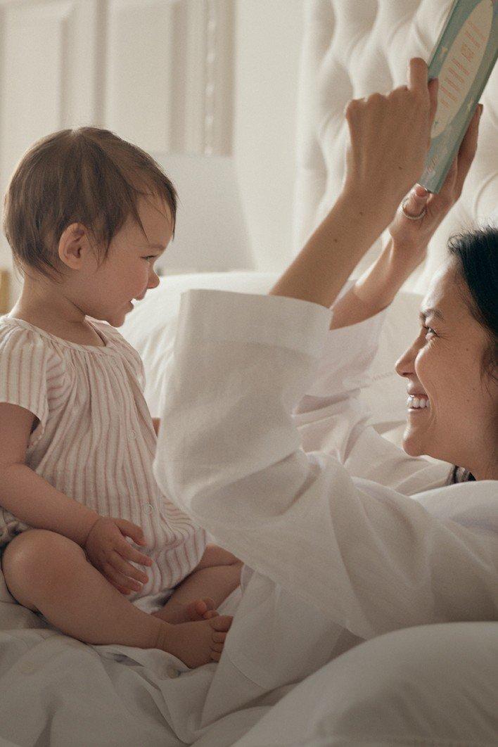 a woman reading a book to a baby in bed