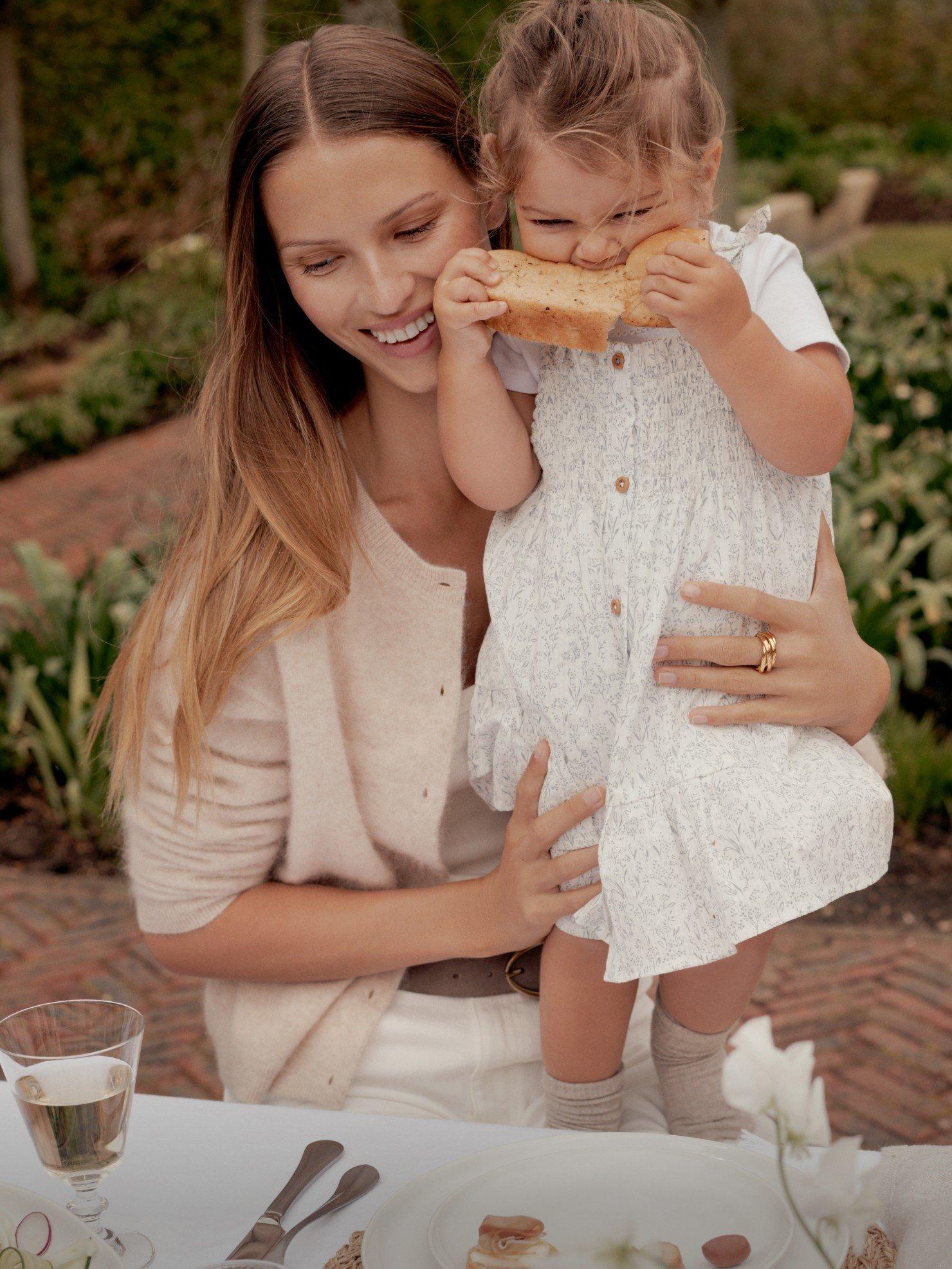 a woman and child eating food at a table outside
