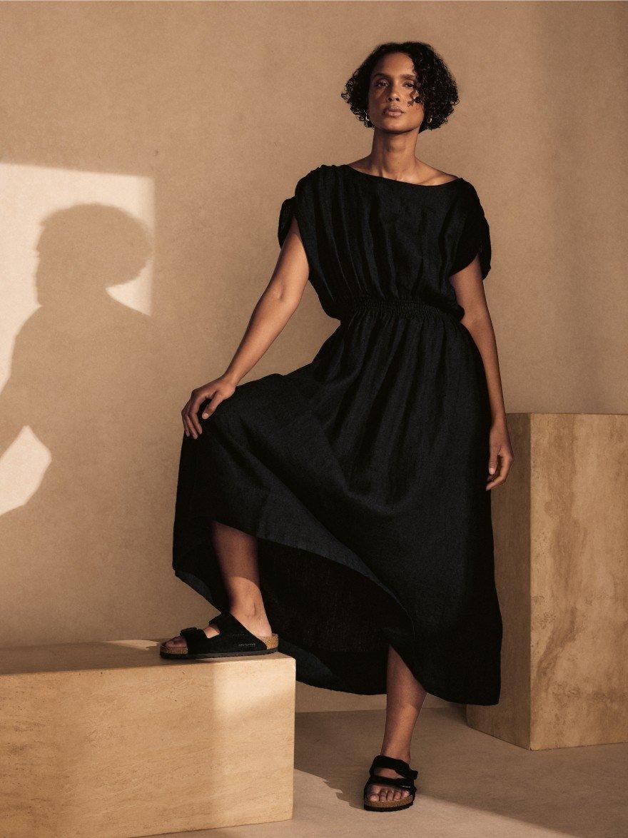 a woman in a black dress standing on a box