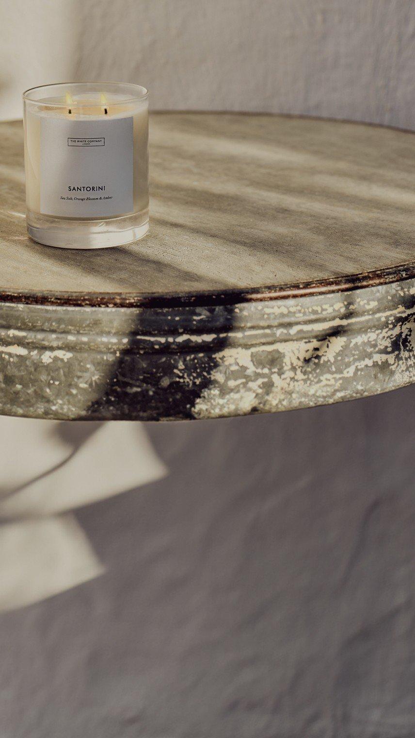 a candle sitting on top of a wooden table next to a glass of water