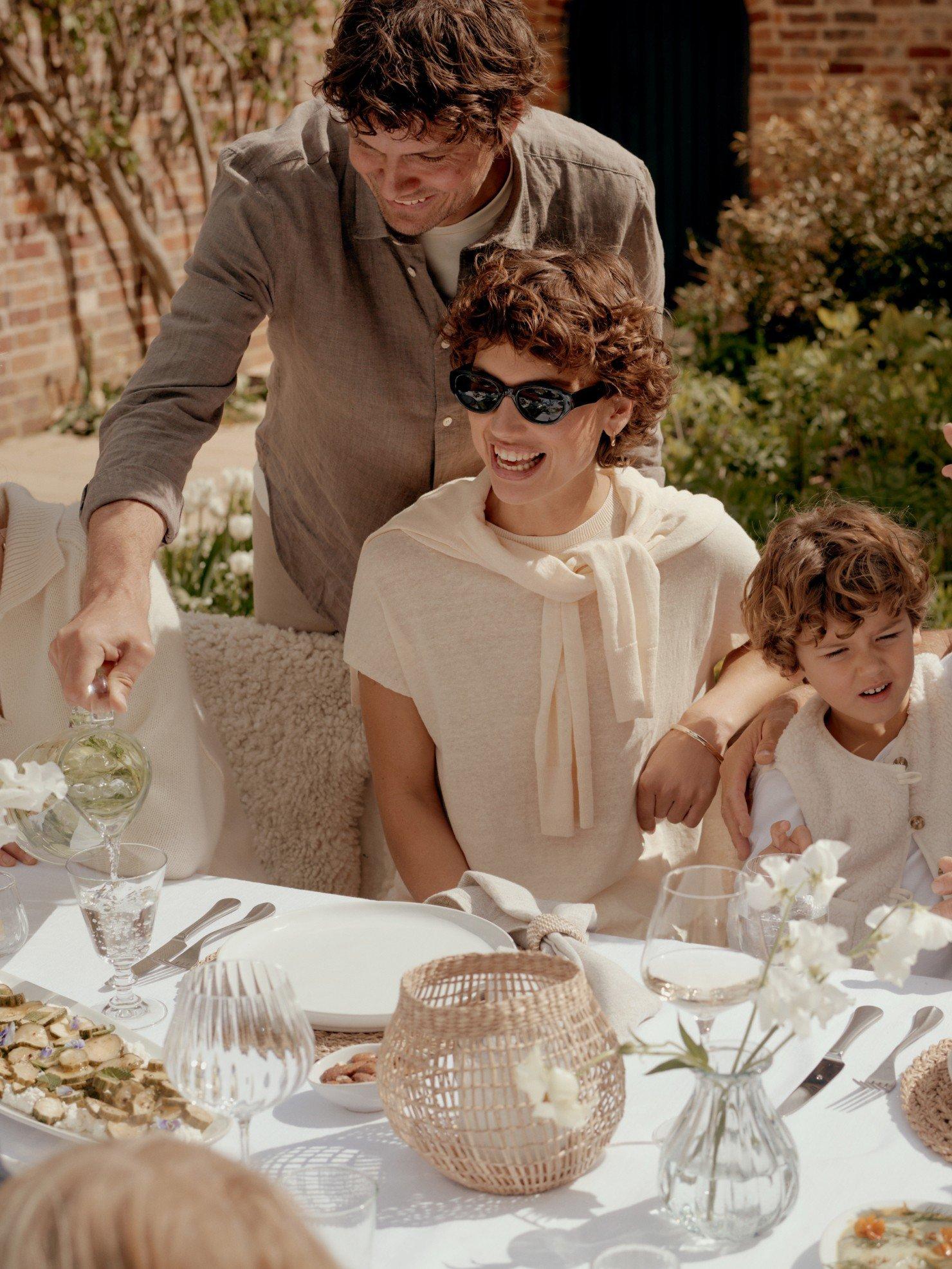 a family of people sitting around a table with food