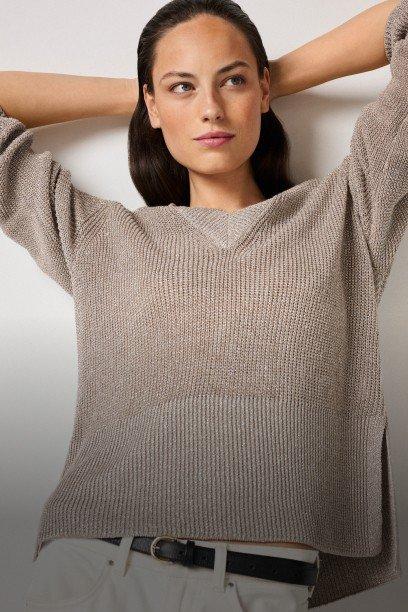 a woman in white pants and a beige sweater