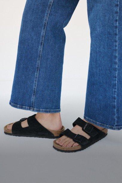 a person wearing sandals and jeans standing on a white background