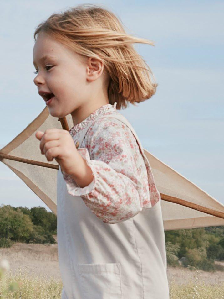 a little girl running through a field with a kite