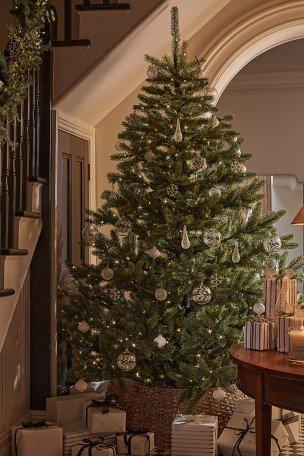 a christmas tree is in the corner of a room with presents underneath