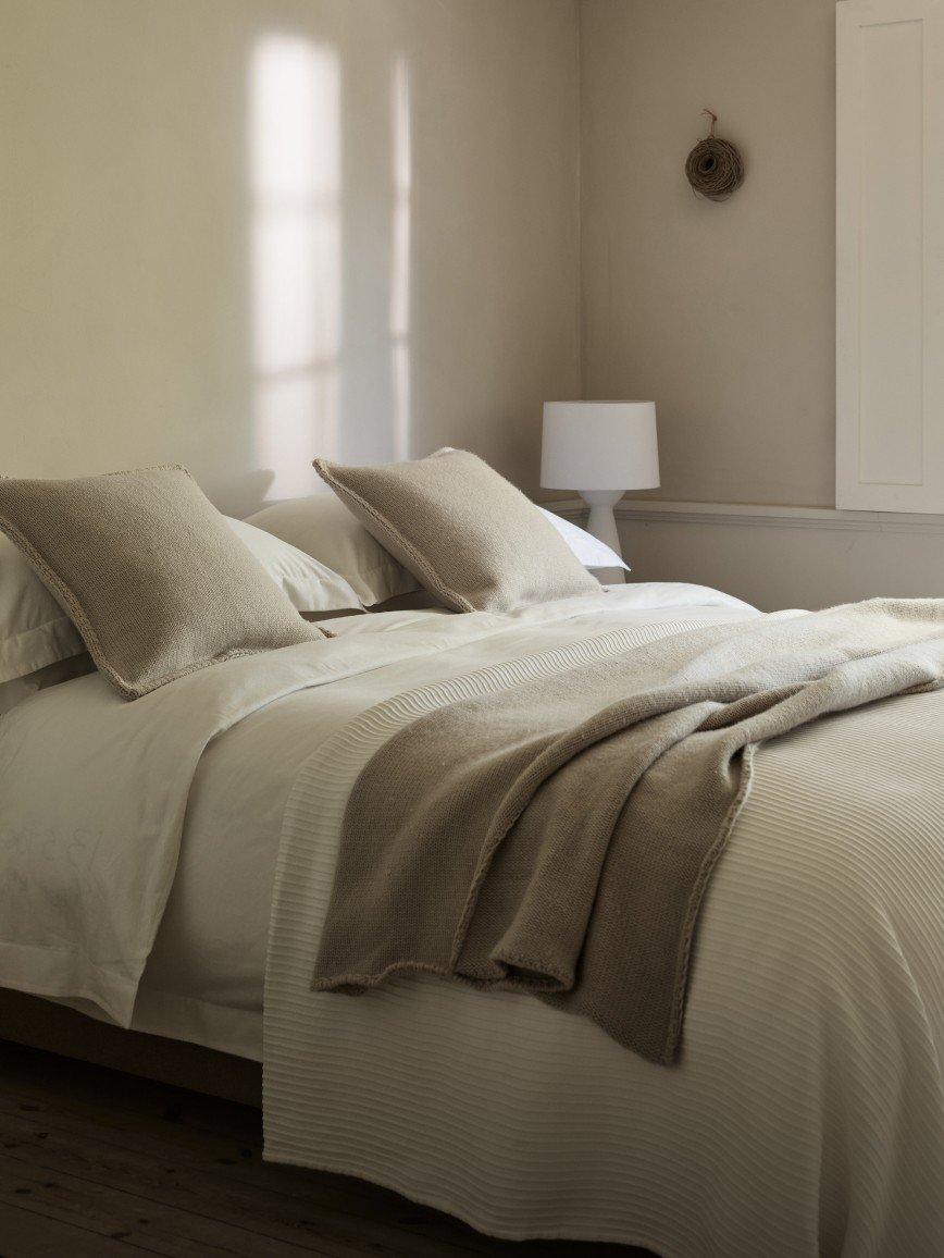 a bed with white sheets and pillows in a bedroom