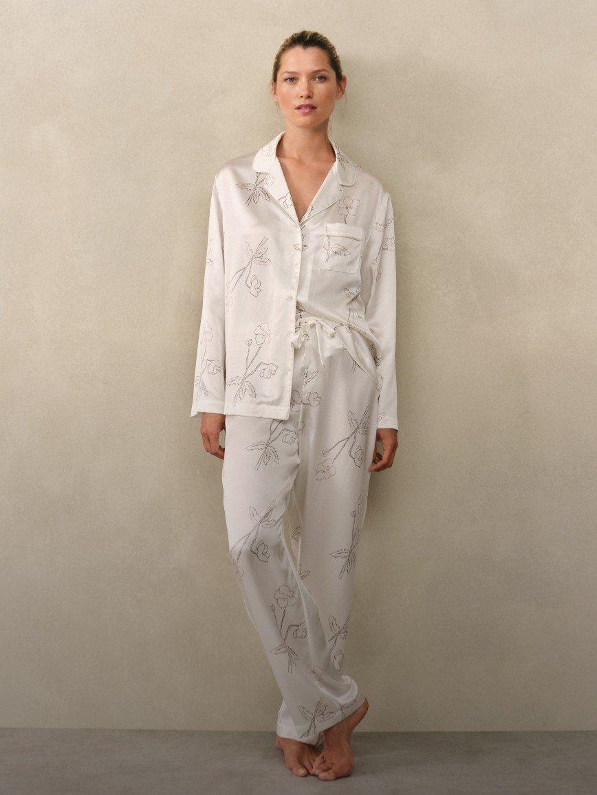 a woman in a white pajama suit poses for a photo