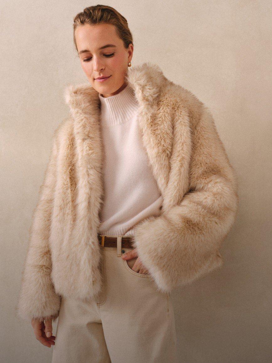 a woman in a white sweater and a fur coat