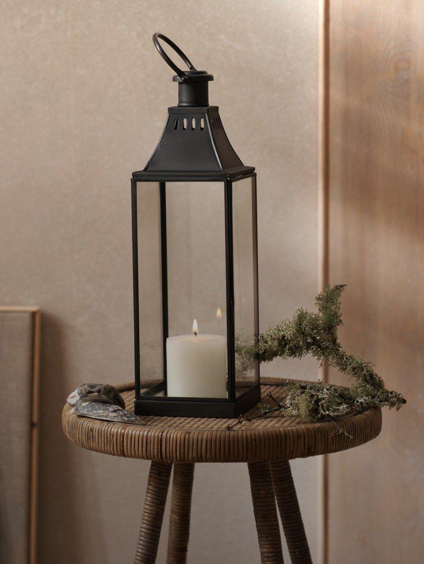 a candle is lit on a table next to a plant