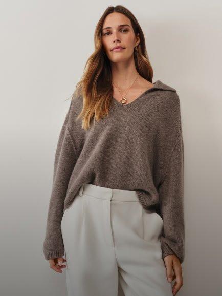 a woman in a white sweater and tan pants posing for a photo