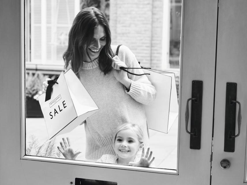 a woman holding a shopping bag with the word sale on it and child