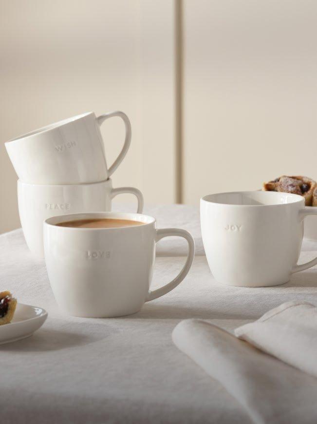 a table with four coffee cups and a plate of pastries