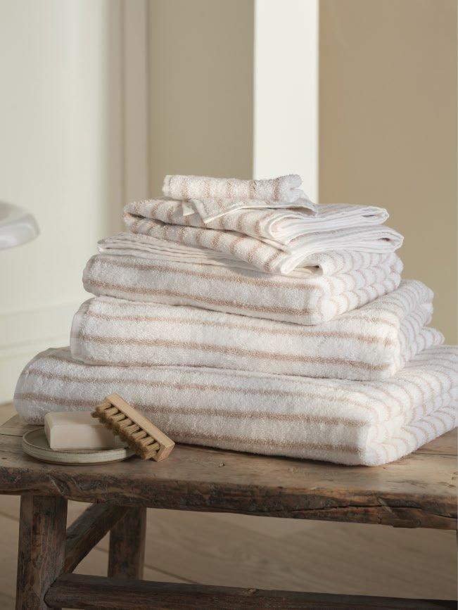 a stack of towels on a wooden table with a soap dish