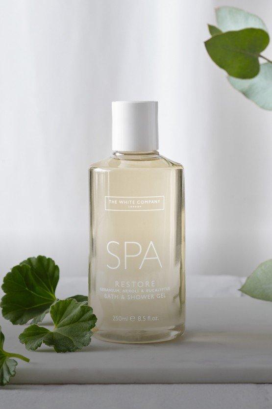 a bottle of spa lotion sitting next to some green leaves