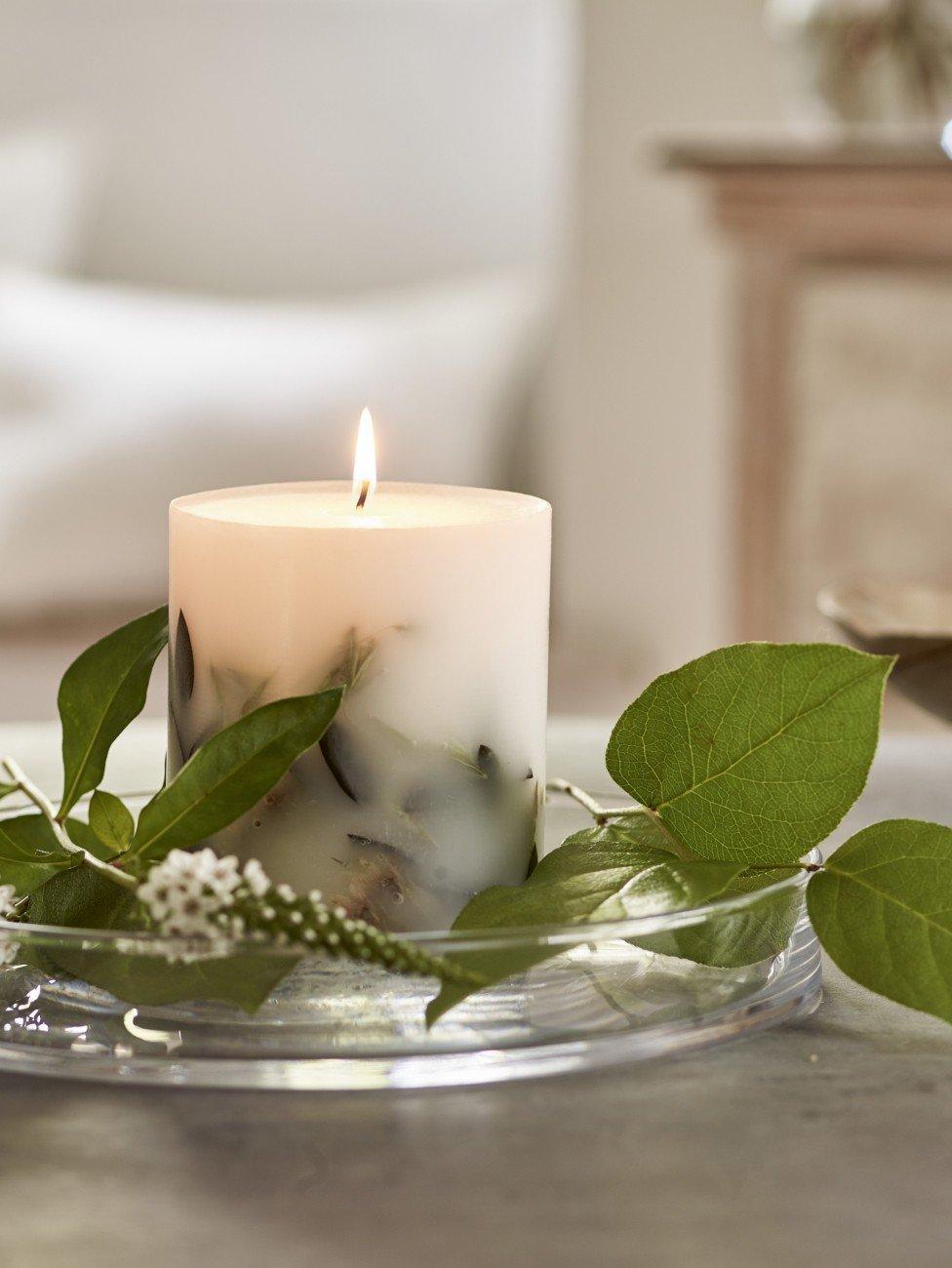 a candle on a glass plate with a green leaf on it