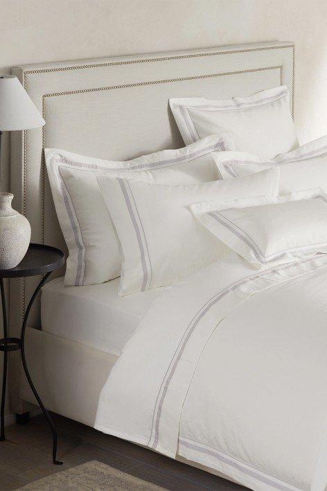 a bed with white sheets and pillows on top of a bed