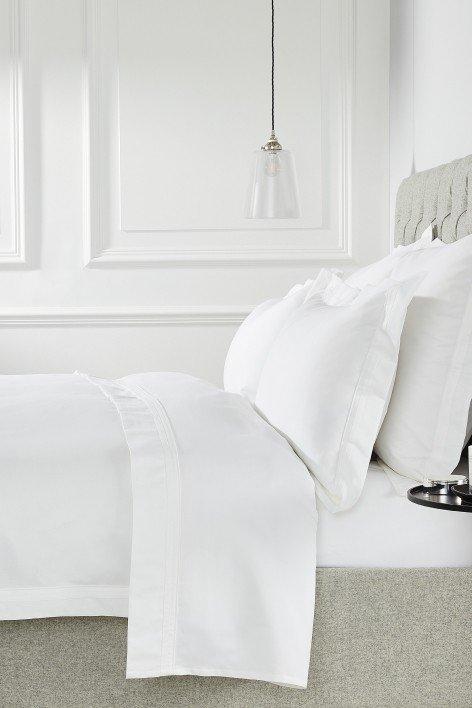 a white bed with a white sheet and a white pillow