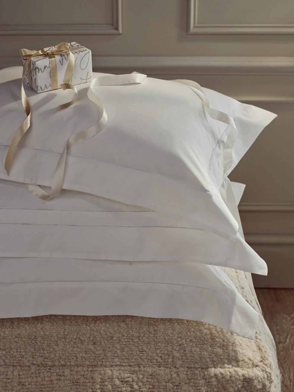 a stack of white pillows with a ribbon tied to them