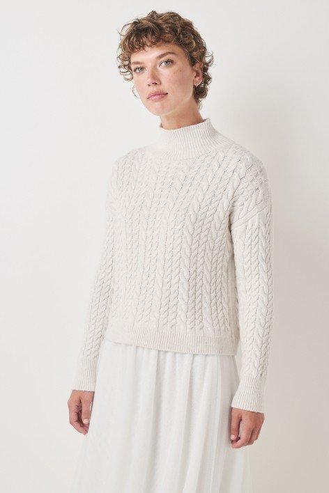 the model is wearing a white sweater and skirt