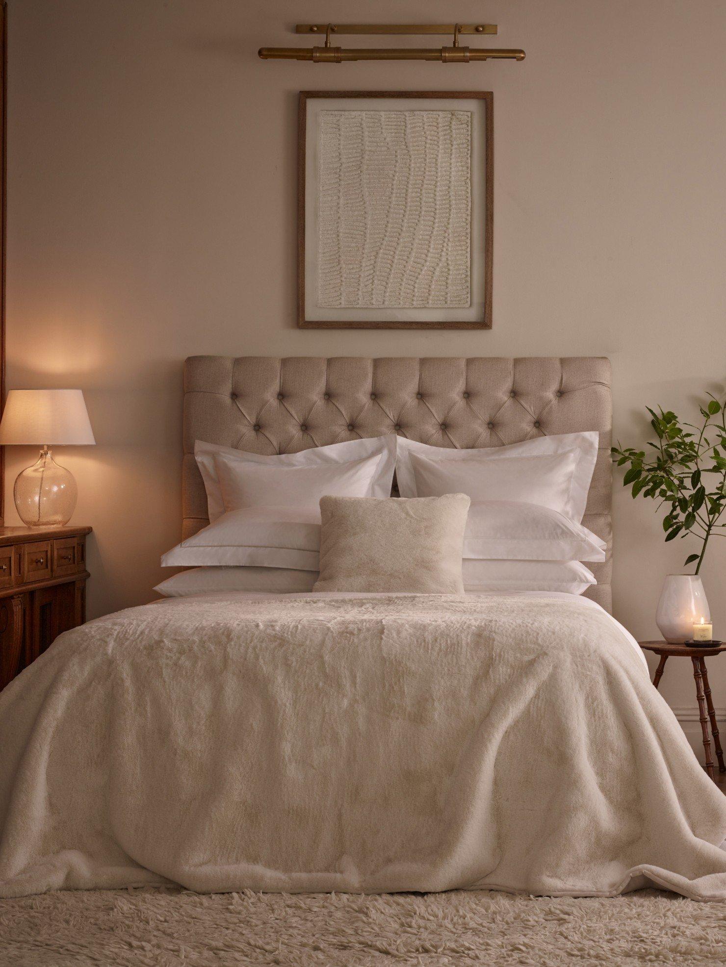 a bed with white sheets and pillows in a bedroom