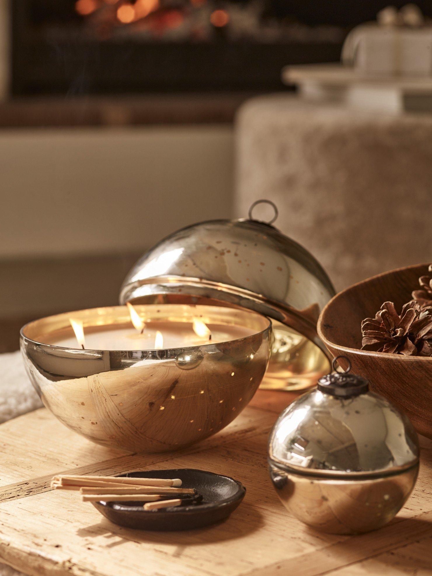 a wooden table with a candle, bowl and a candle holder