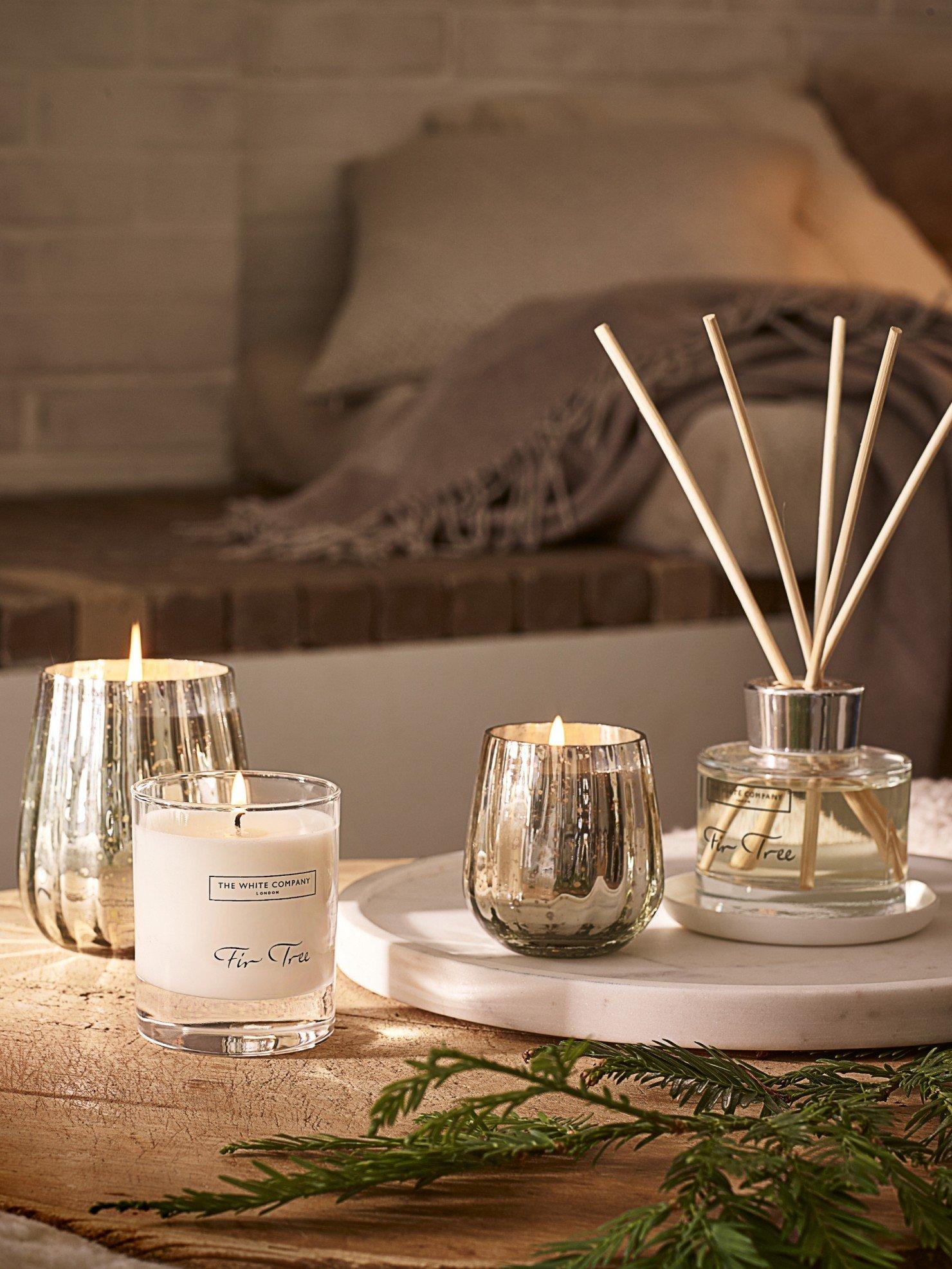 a table with a candle, a diffuser and some reeds