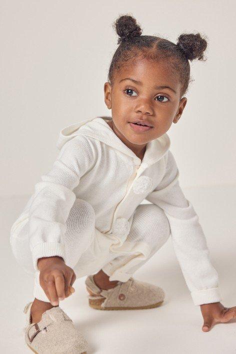 a baby's white outfit is on a pillow next to a box