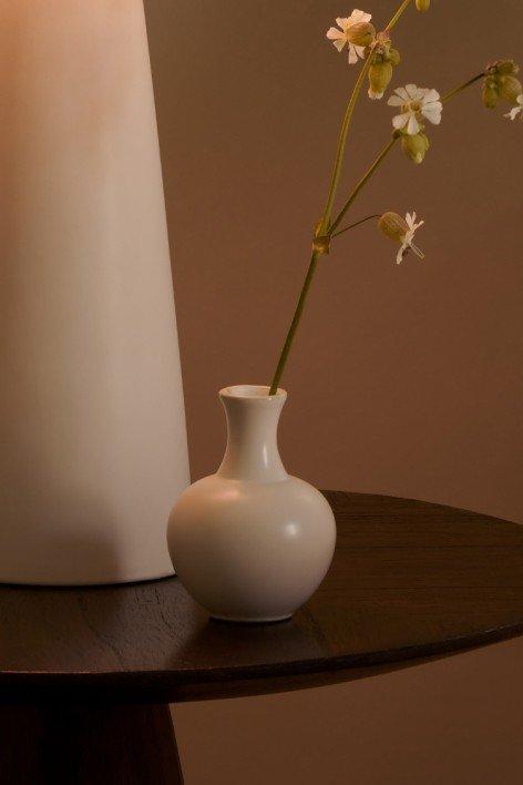 a vase with flowers on a table next to a lamp