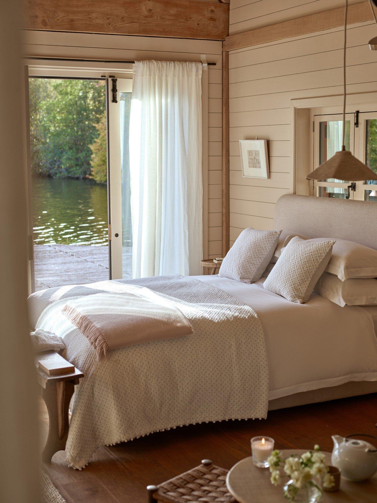 a bedroom with a bed, a table, a lamp, and a door