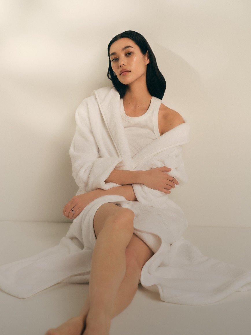 a woman in a white robe sitting on a white floor