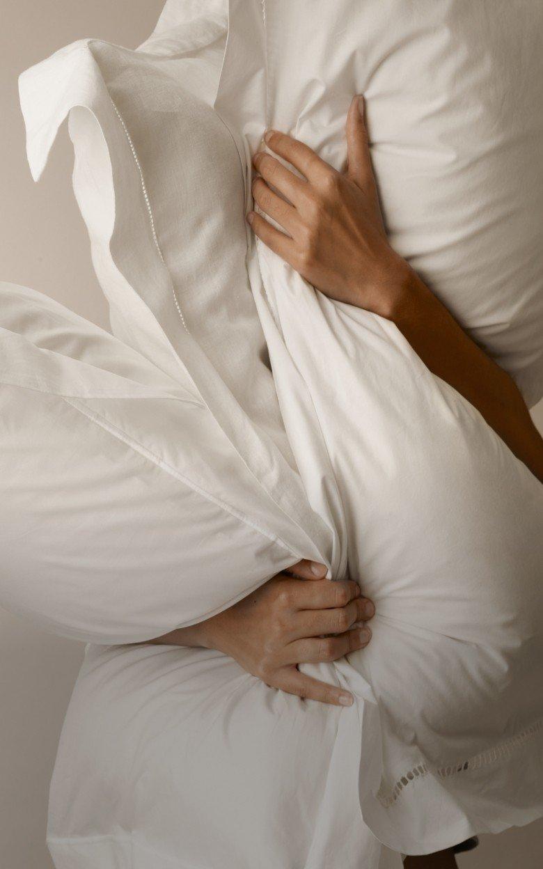 a person is wrapped in a white sheet with pillows