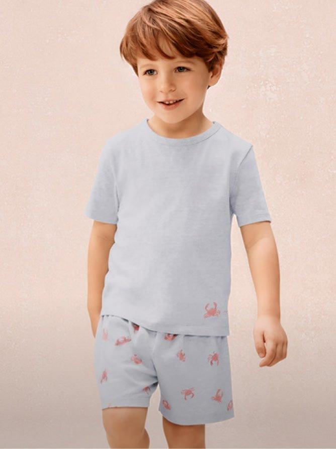 a young boy in a white shirt and shorts walking