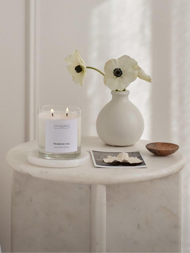 a white table with a candle and a vase of flowers
