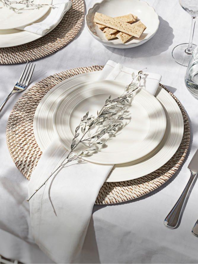a table setting with a white plate and silverware on a white tablecloth