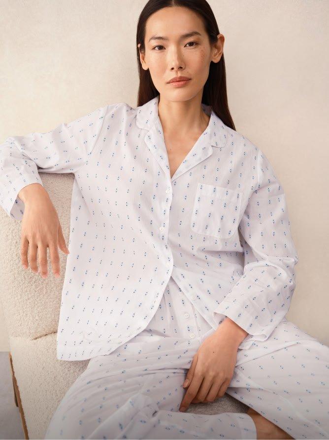 a woman in a white pajama top and pants sitting on a chair