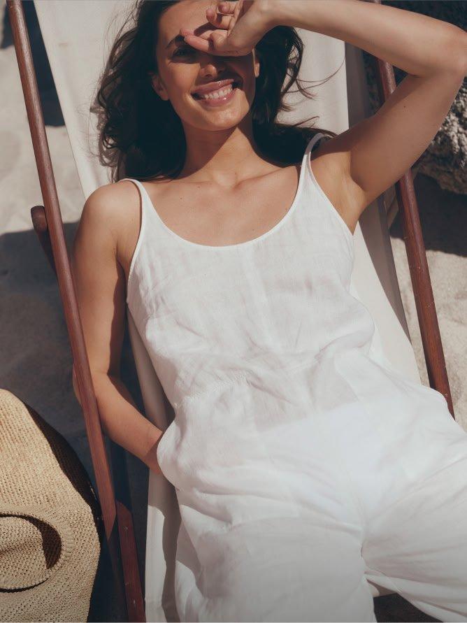 a woman in white dress laying in a chair with sunglasses on