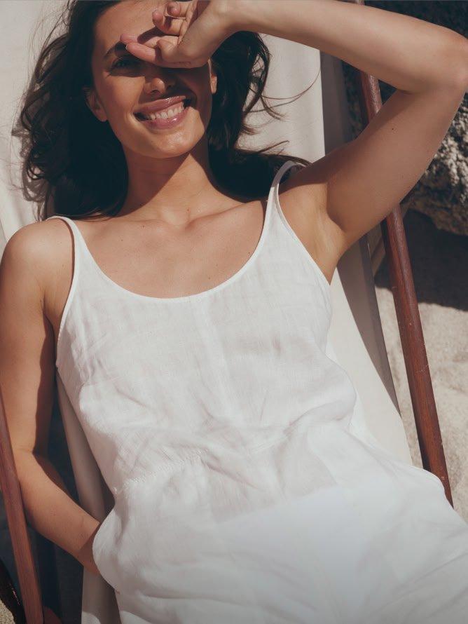 a woman in white dress laying in a chair with sunglasses on