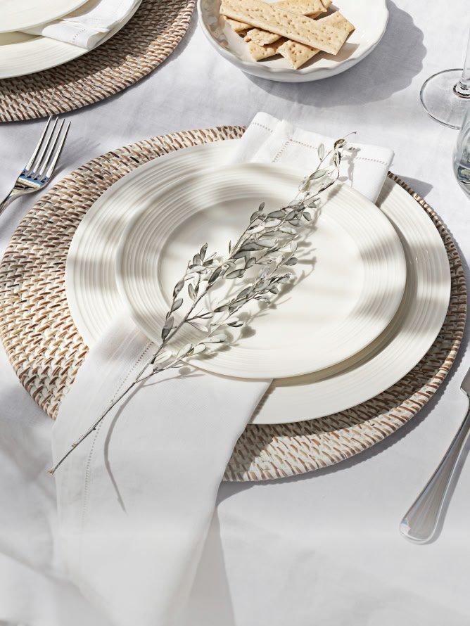 a table setting with a white plate and silverware on a white tablecloth