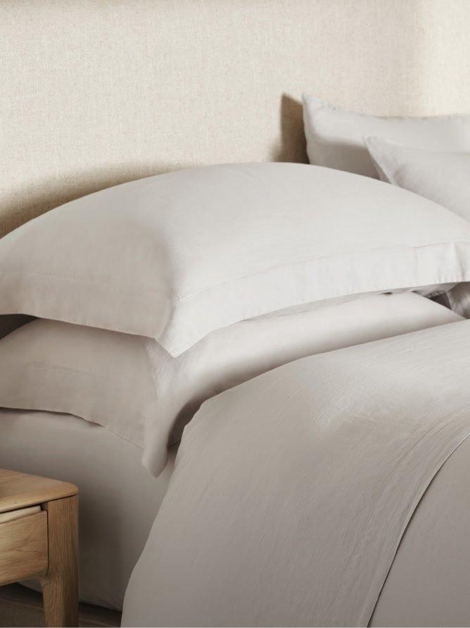 a bed with white sheets and pillows on a wooden bed frame