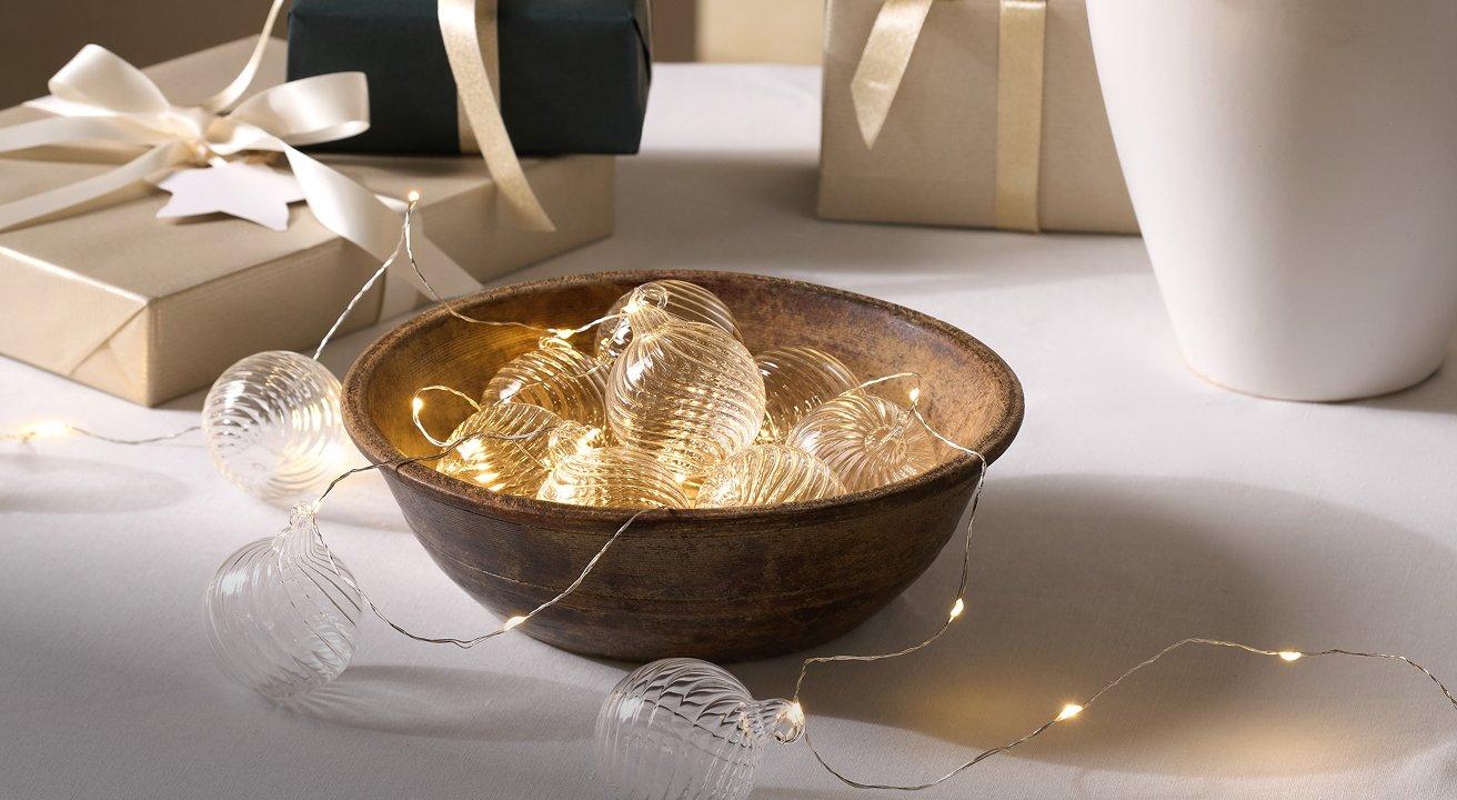 a bowl of presents with lights on top of a table