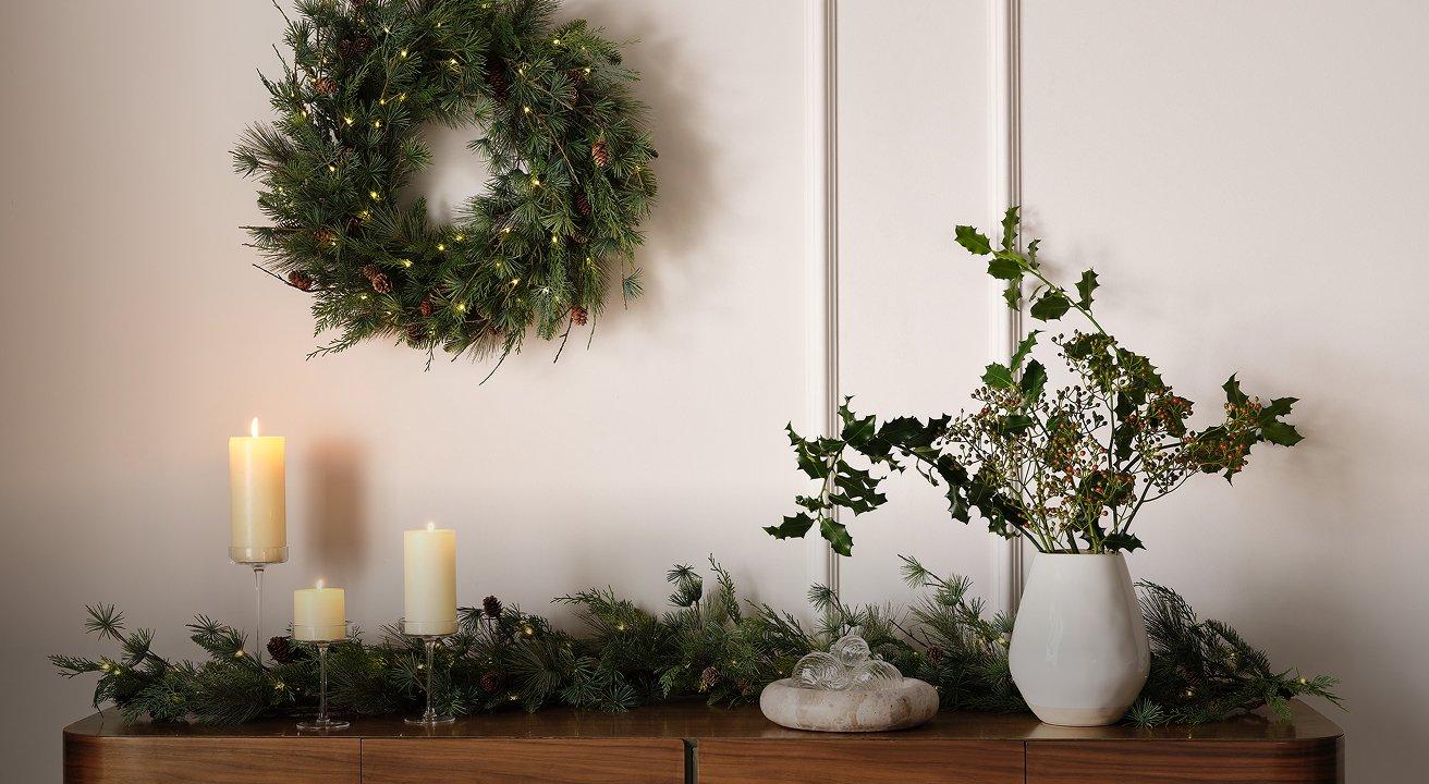 a wreath on a dresser with candles and a wreath on the wall